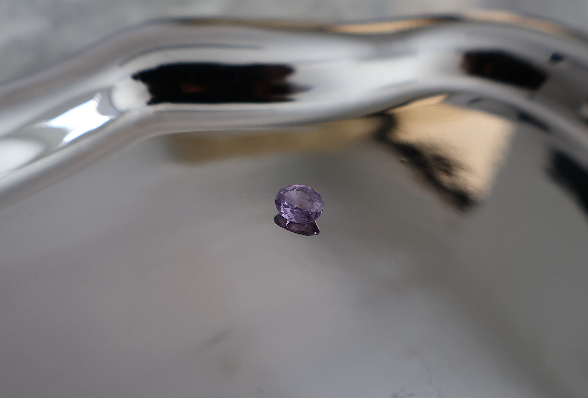Purple gemstone on a reflective metallic surface