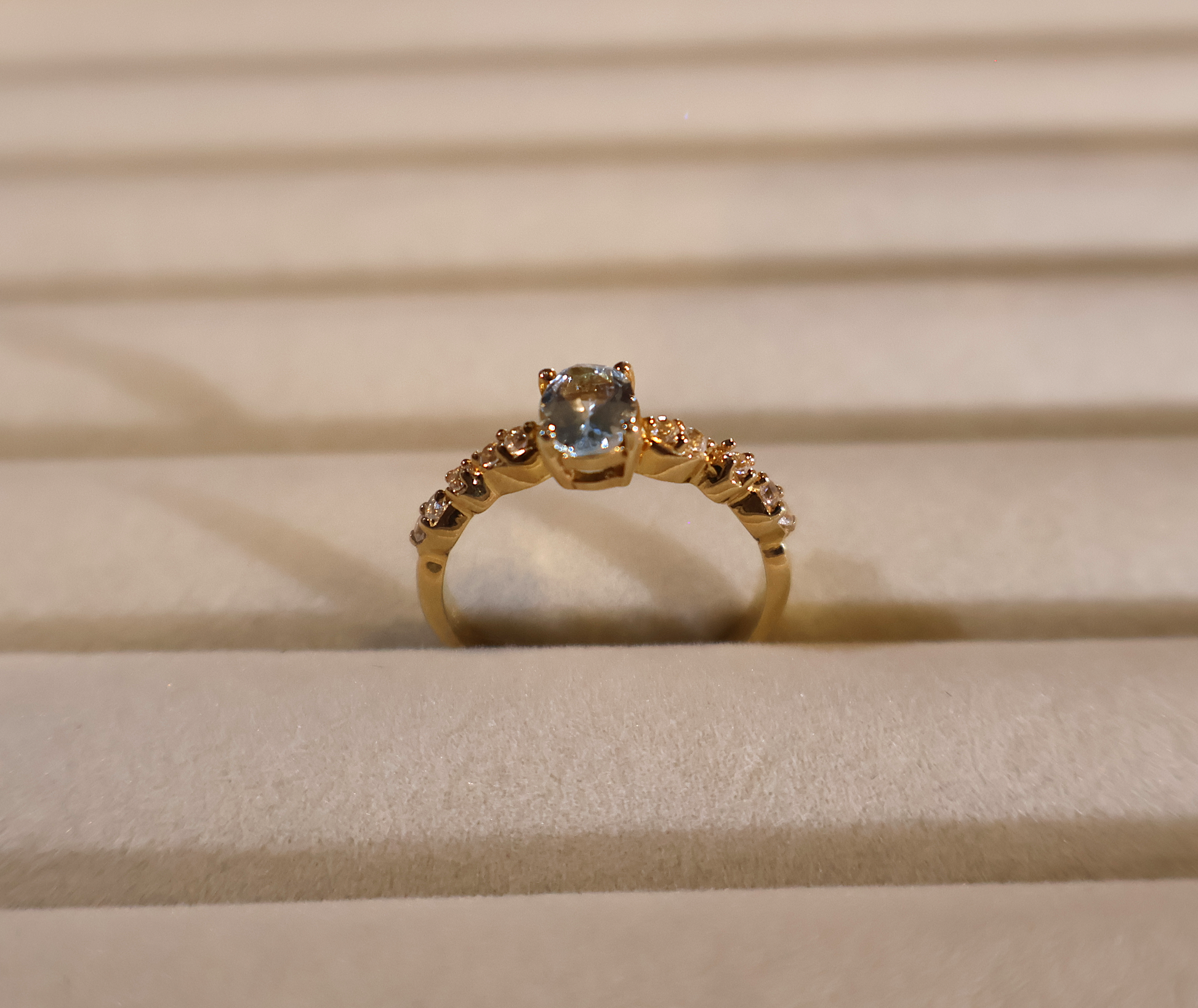 Gold ring with a blue gemstone aquamarine on a beige fabric background