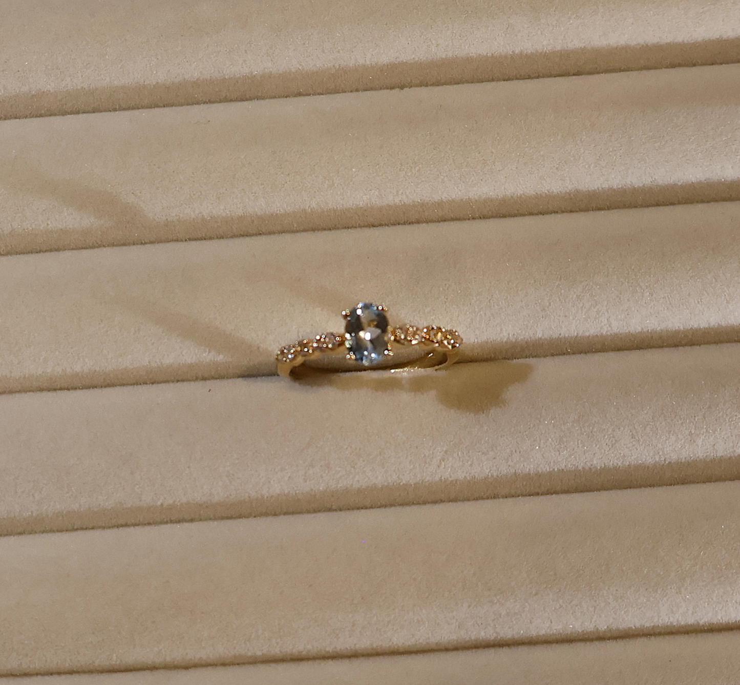 Gold ring with a blue gemstone aquamarine on a beige fabric background