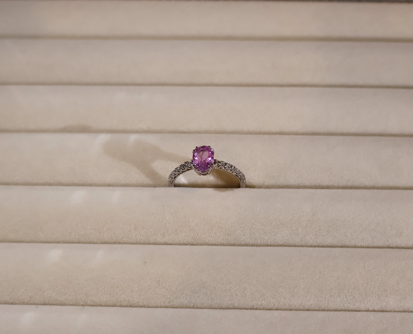 White gold Ring with a pink sapphire gemstone on a beige background
