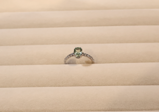 White gold ring with a green gemstone peridot on a beige fabric background