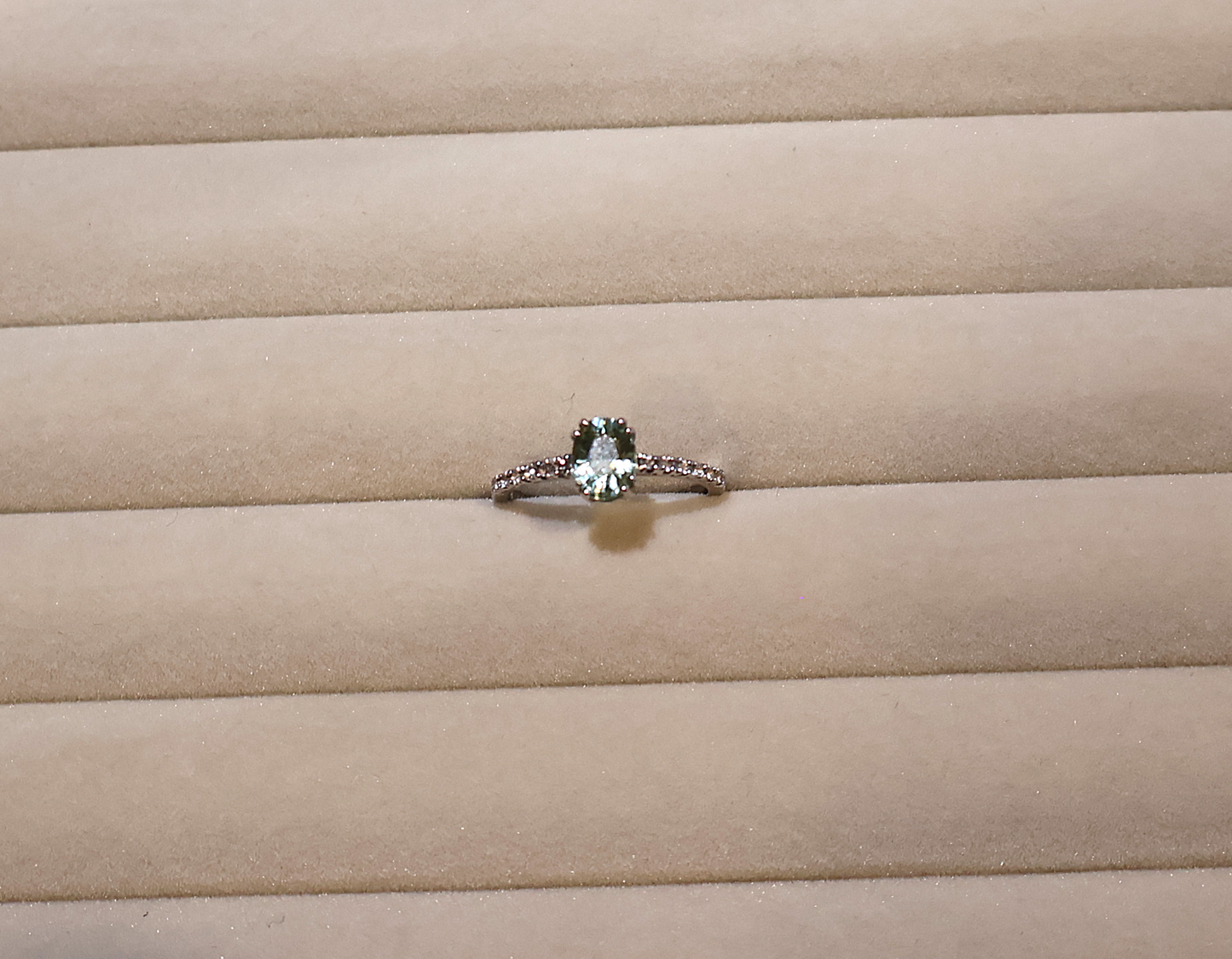 White gold ring with a green gemstone peridot on beige fabric