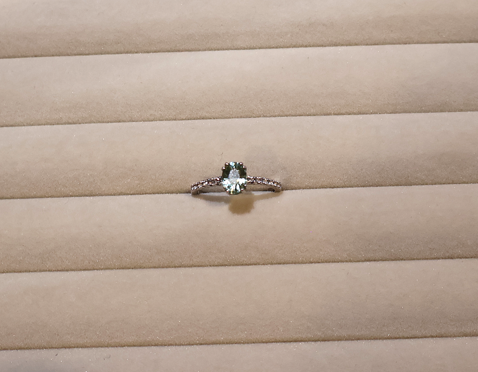 White gold ring with a green gemstone peridot on beige fabric